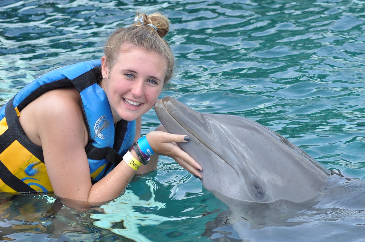 Katie smiling beside a dolphin in the water