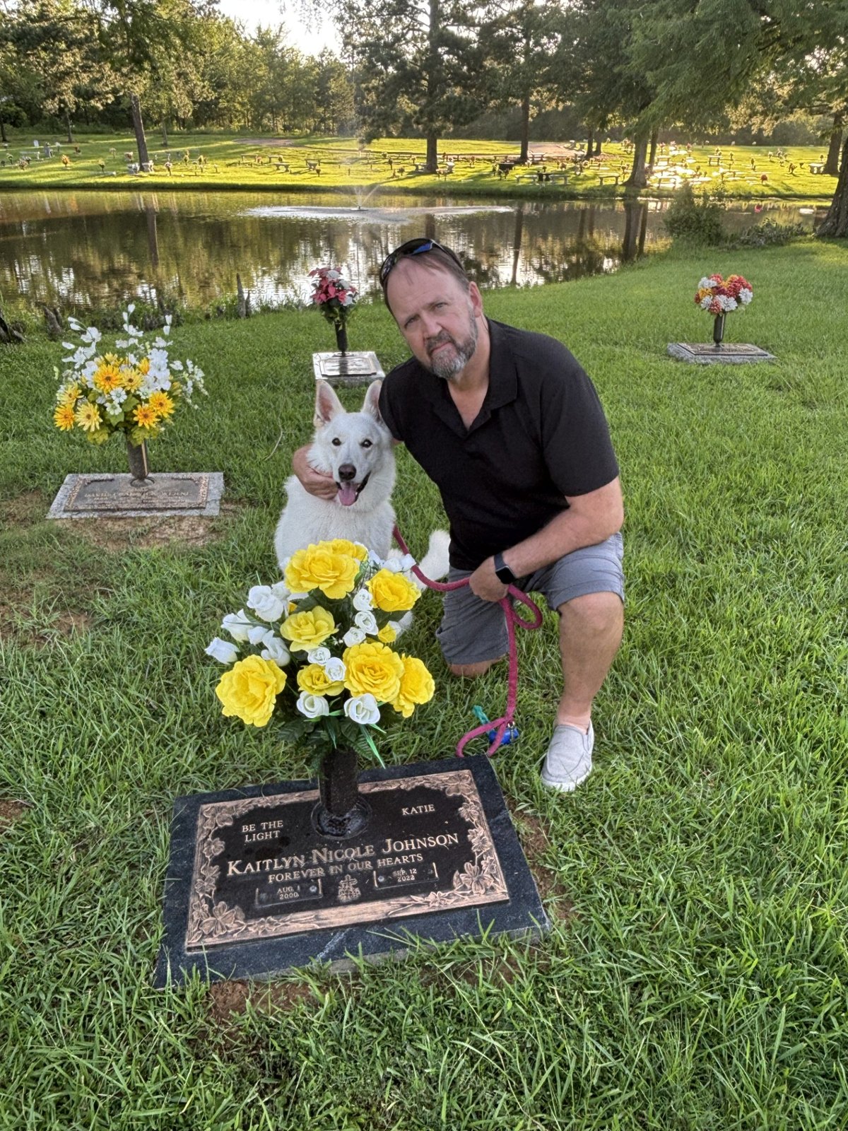 Richard and Katie’s dog Remi visiting Katie’s gravesite, with yellow and white flowers